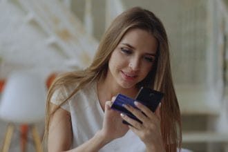 Mở thẻ tín dụng bị từ chối nợ xấu: Woman using smartphone for online shopping with her credit card at home.