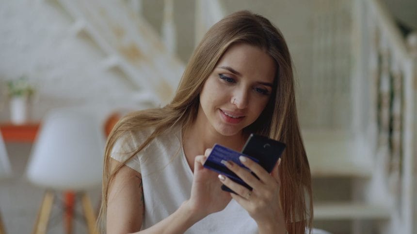 Mở thẻ tín dụng bị từ chối nợ xấu: Woman using smartphone for online shopping with her credit card at home.