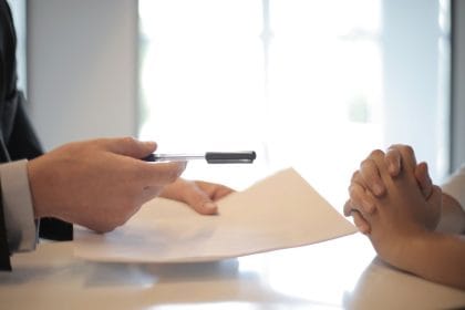 Tất toán khoản vay trước hạn: Side view of faceless formal man giving pen and paper to focused female with clenched hands at table on meeting