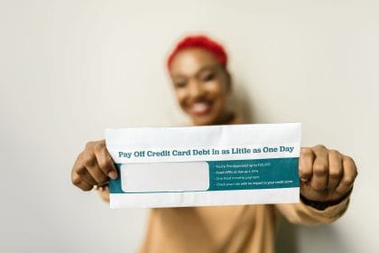 Vay tiêu dùng trả góp: Woman presenting an envelope with a credit card debt offer, blurred background.