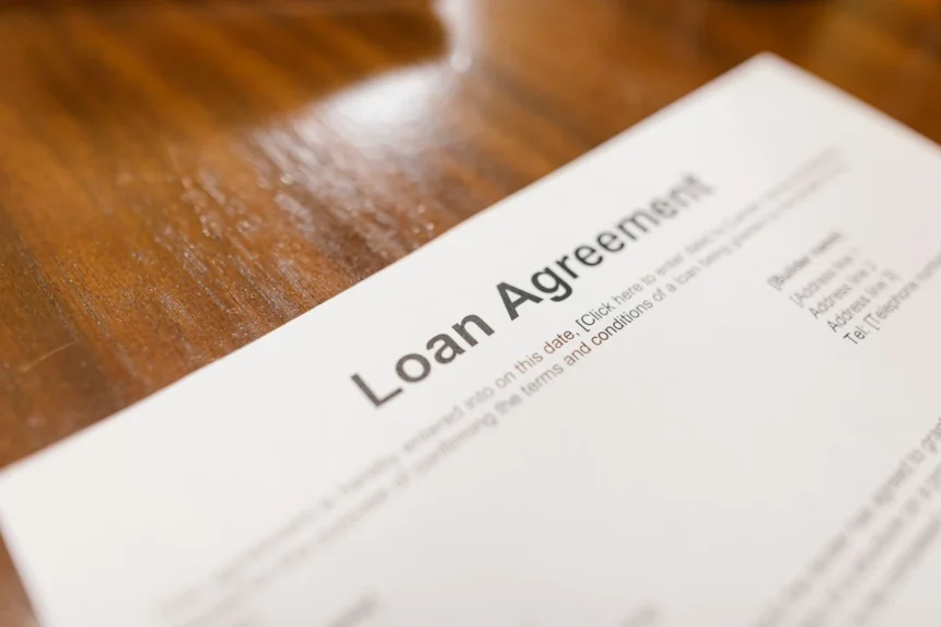 Vay tín chấp lãi suất thấp: Detailed loan agreement document close-up on a wooden table representing legal and financial concepts.