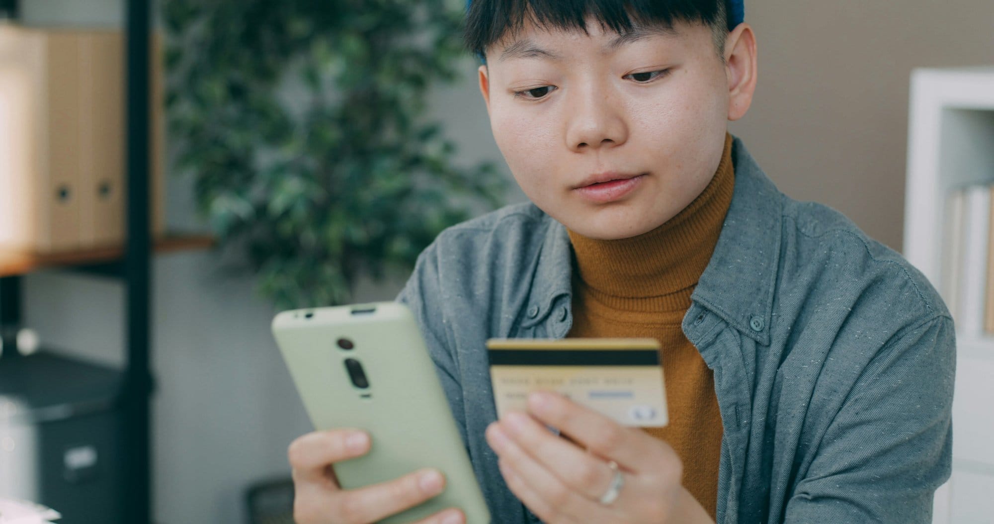 Người đàn ông ngồi bàn xem điện thoại đăng ký vay online
