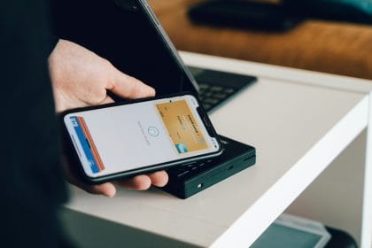 VN Finance: A person holding a smartphone over a card reader for contactless payment